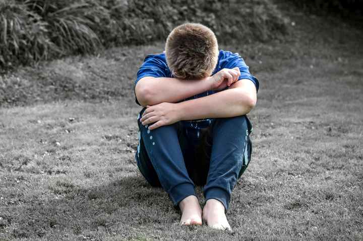 rear view of a boy sitting on grassland