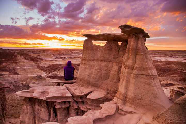 woman wearing purple top surrounded gray mountains under gray and white cloudy sky