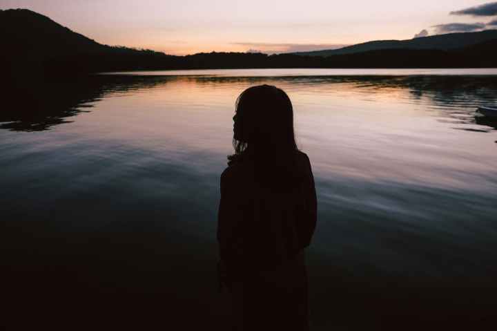 silhouette of woman standing near body of water
